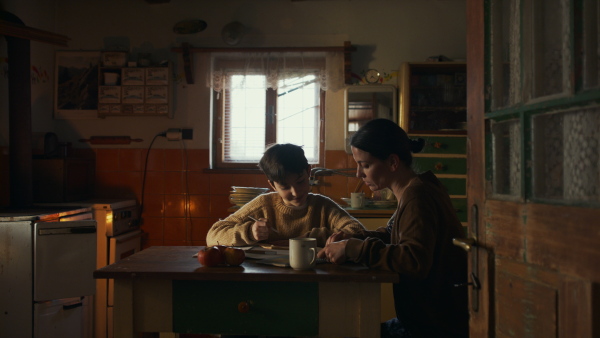 Portrait of sad poor mother helping small daughter with school indoors at home, poverty concept.