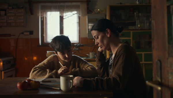 Portrait of sad poor mother helping small daughter with school indoors at home, poverty concept.