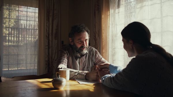 Unhappy poor mature couple comforting each other indoors at home, poverty concept.