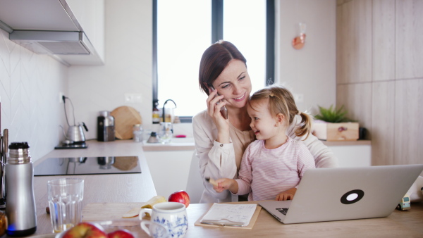 Mother working at home, playing with her daughter. Homeoffice concept.