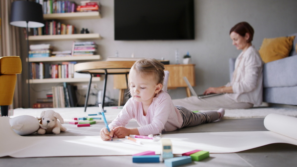 Beautiful girl at home drawing a picture while her parents are working. Homeoffice concept.