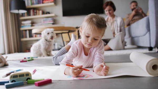 Beautiful girl at home drawing a picture while her parents are working. Homeoffice concept.