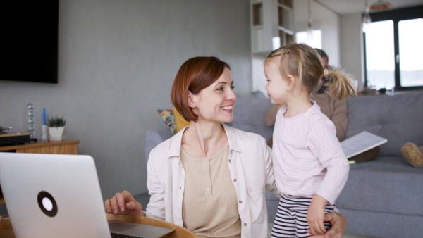 Portrait of mother taking care of her daughter while making a call. Homeoffice concept.