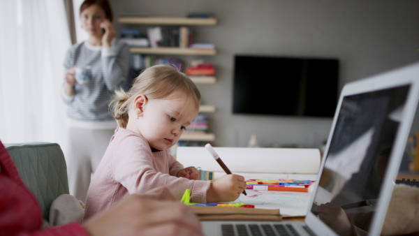 Beautiful girl at home drawing a picture while her parents are working. Homeoffice concept.