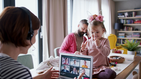 Portrait of mother taking care of her daughter while having a call. Homeoffice concept.