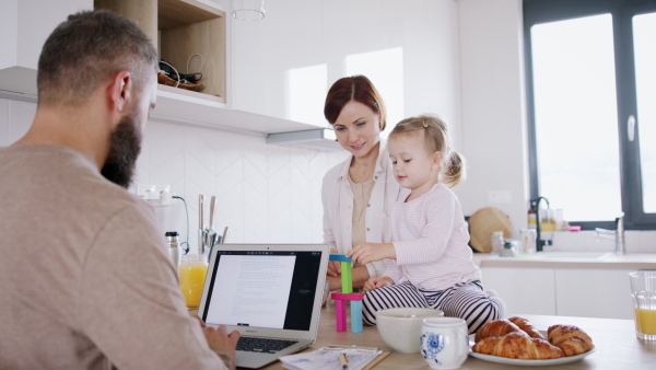 Father working at home, having fun with his family. Homeoffice concept.