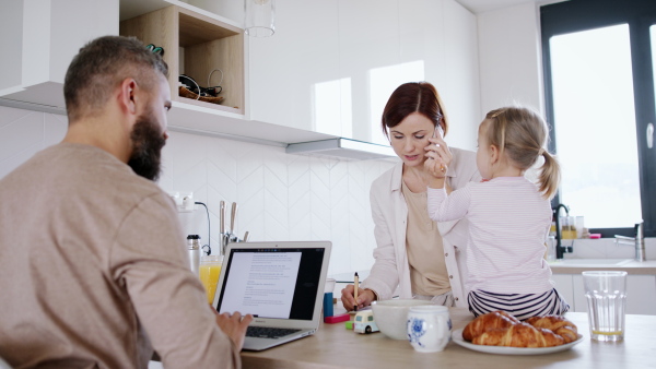 Portrait of mother taking care of her daughter while making a call. Homeoffice concept.