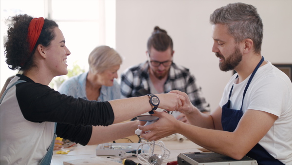 A group of old and young people at repair cafe repairing household electrical devices.