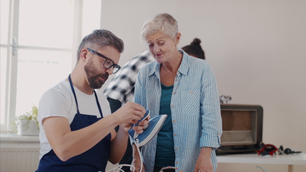 A group of old and young people at repair cafe repairing household electrical devices.