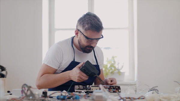 A mature man at repair cafe repairing household electrical devices.