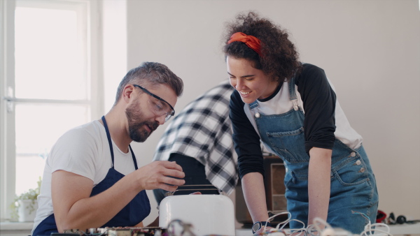 A group of people at repair cafe repairing household electrical devices.