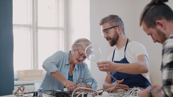 A group of old and young people at repair cafe repairing household electrical devices.