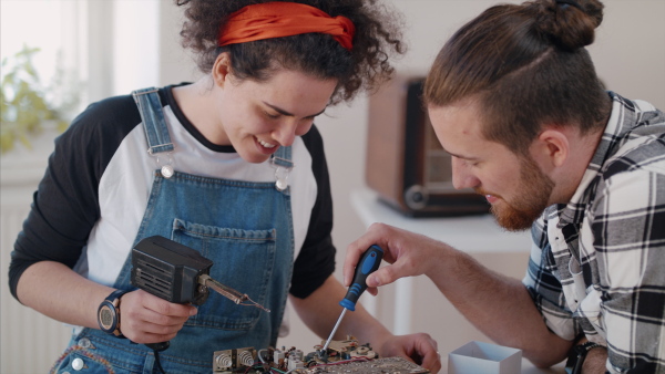 A young couple at repair cafe repairing household electrical devices, talking.