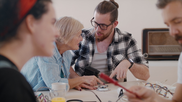 A group of old and young people at repair cafe repairing household electrical devices.