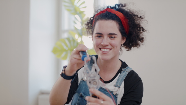 Front view of young woman at repair cafe repairing household electrical devices.