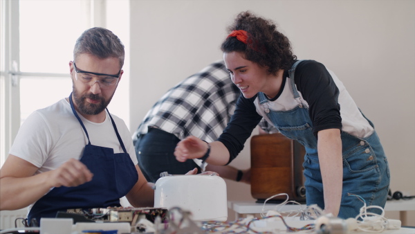 A group of people at repair cafe repairing household electrical devices.