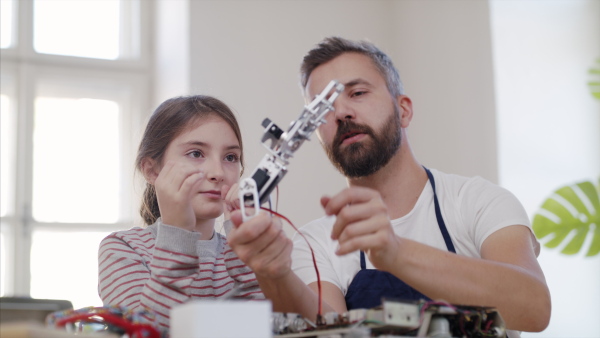 Small girl with mature man at repair cafe repairing household electrical devices.