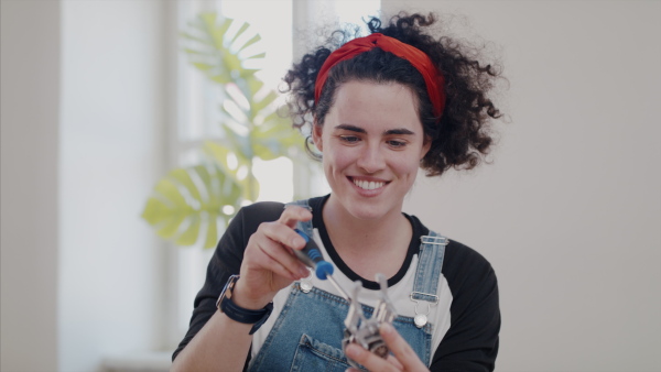 Front view of young woman at repair cafe repairing household electrical devices.