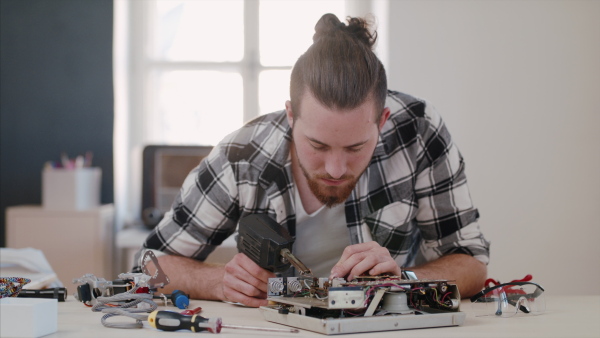 A young man at repair cafe repairing household electrical devices.