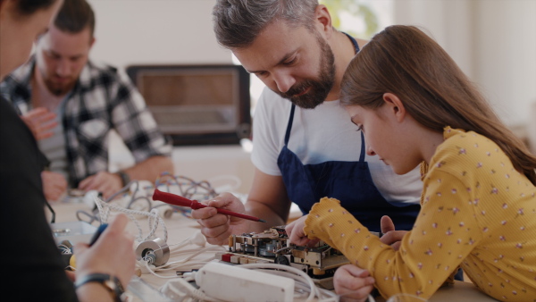 A group of old and young people at repair cafe repairing household electrical devices.