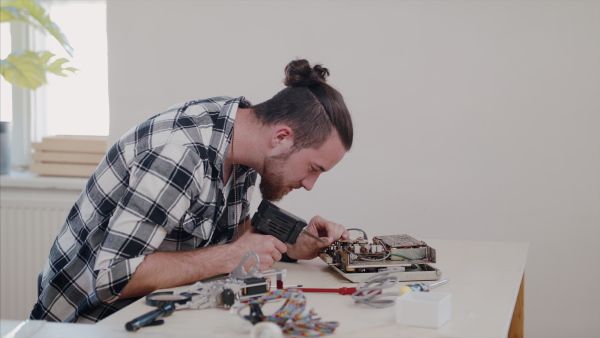 A young man at repair cafe repairing household electrical devices.