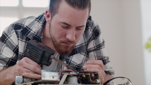 A young man at repair cafe repairing household electrical devices.