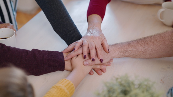 A midsection of group of people at community centre, stacking hands together.