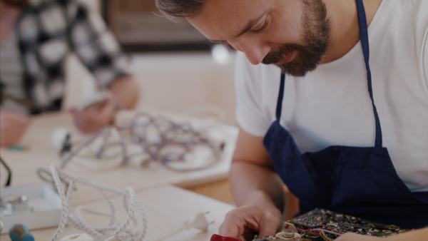 A mature man at repair cafe repairing household electrical devices.