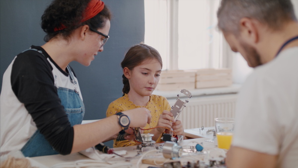 A group of old and young people at repair cafe repairing household electrical devices.