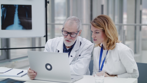 Doctors with laptop sitting and talking at the desk, corona virus concept.