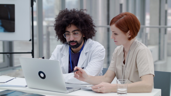 Doctors with laptop sitting and talking at the desk, corona virus concept.