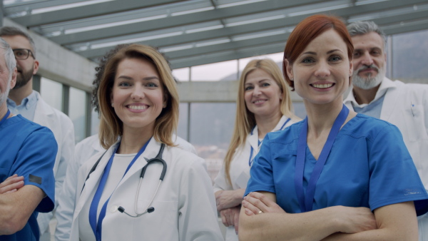 A group of doctors standing in hospital corridor on medical conference, looking at camera. Slow motion.