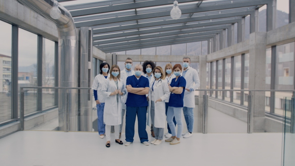 A group of doctors with face masks looking at camera, corona virus concept.