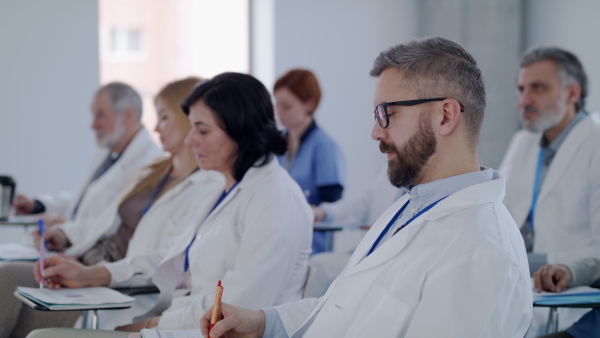 A group of doctors listening to presentation about corona virus on conference.