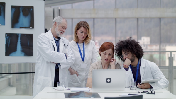 A group of doctors with laptop at the desk discussing issues.