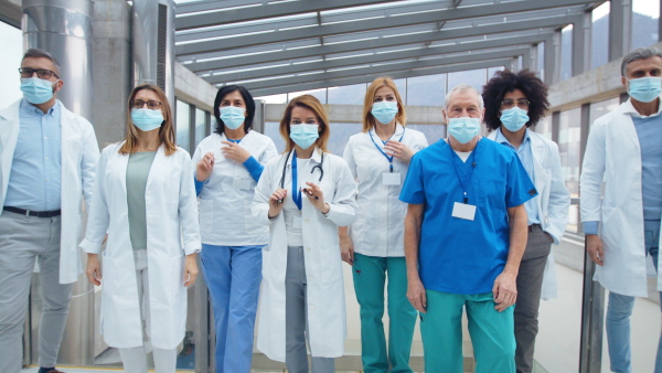 Group of doctors with face masks in hurry running in corridor of hospital, emergency concept.