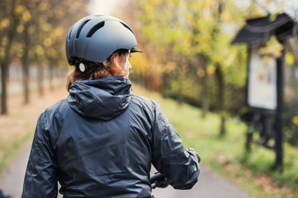 A rear view of active senior woman with bicycle helmet standing outdoors. Copy space.