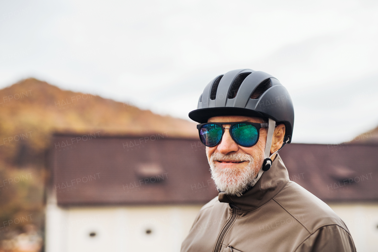 Active senior man with bike helmet and sunglasses standing outdoors in town. Copy space.