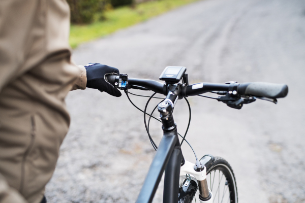 A midsection of an unrecognizable cyclist with electrobike standing outdoors in town.