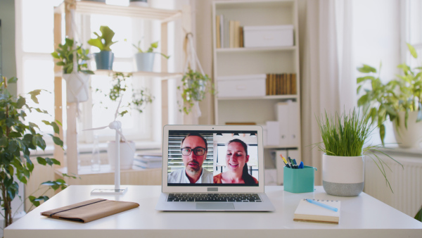 Man and woman talking on laptop on desk in business office, video call concept.