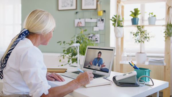 Senior woman with laptop indoors at home , consulting doctor and video call concept.