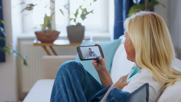 Senior woman with smartphone indoors at home , consulting doctor and video call concept.