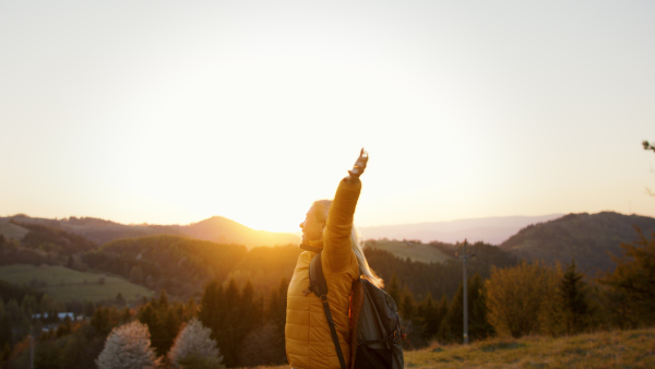 Attractive senior woman stretching arms outdoors in nature, meditating at sunset.