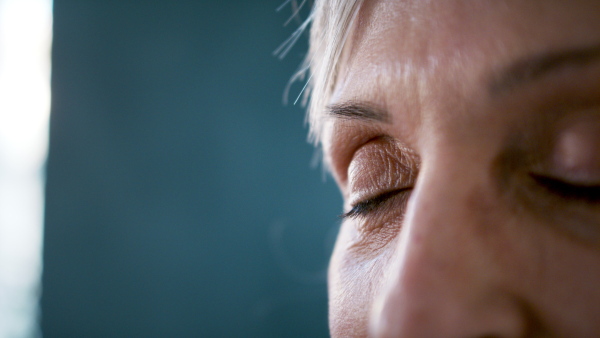 Front view close up of senior womans face, opening her eyes.