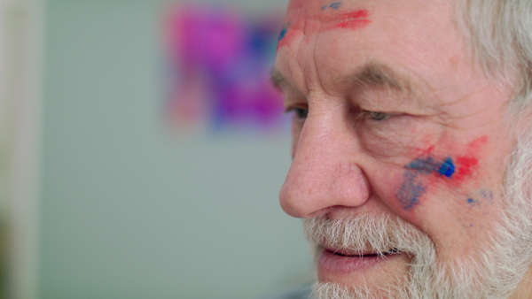 Close-up of happy senior man painting pictures in art class. Slow motion.