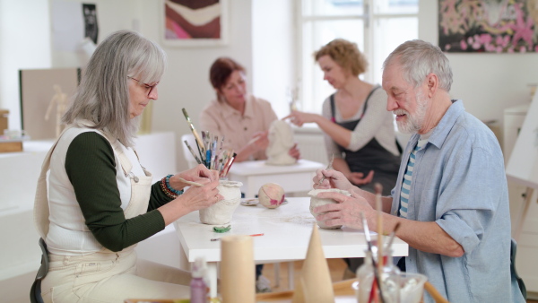 Group of happy senior people with teacher working with clay on ceramics workshop.