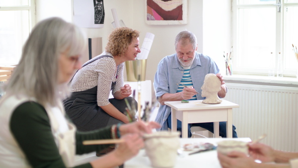 Group of happy senior people with teacher working with clay on ceramics workshop.