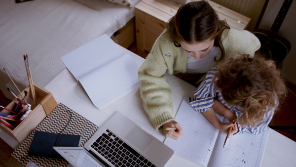 Top view of sisters schoolgirls learning online indoors at home, coronavirus concept.