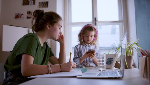 Teenager schoolgirl with face mask learning online indoors at home, coronavirus concept.