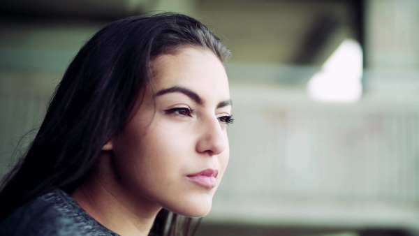 A close-up portrait of a beutiful woman standing under the bridge in the city. Slow motion. Copy space.